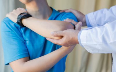 muscular man with shoulder ache exercising with physiotherapist